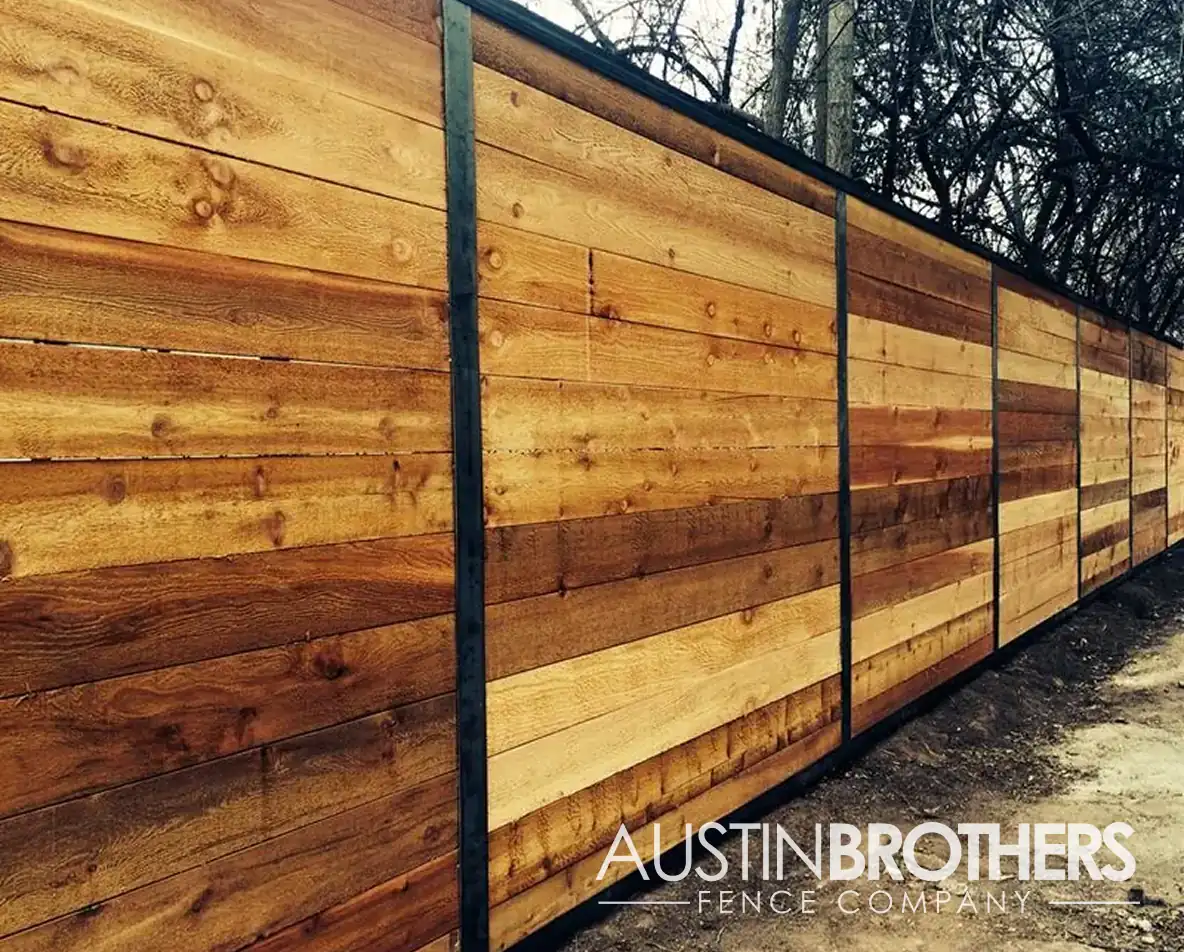 Long horizontal wood fence with black steel posts.