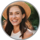 Headshot of a woman with medium-length dark hair in a straw hat.
