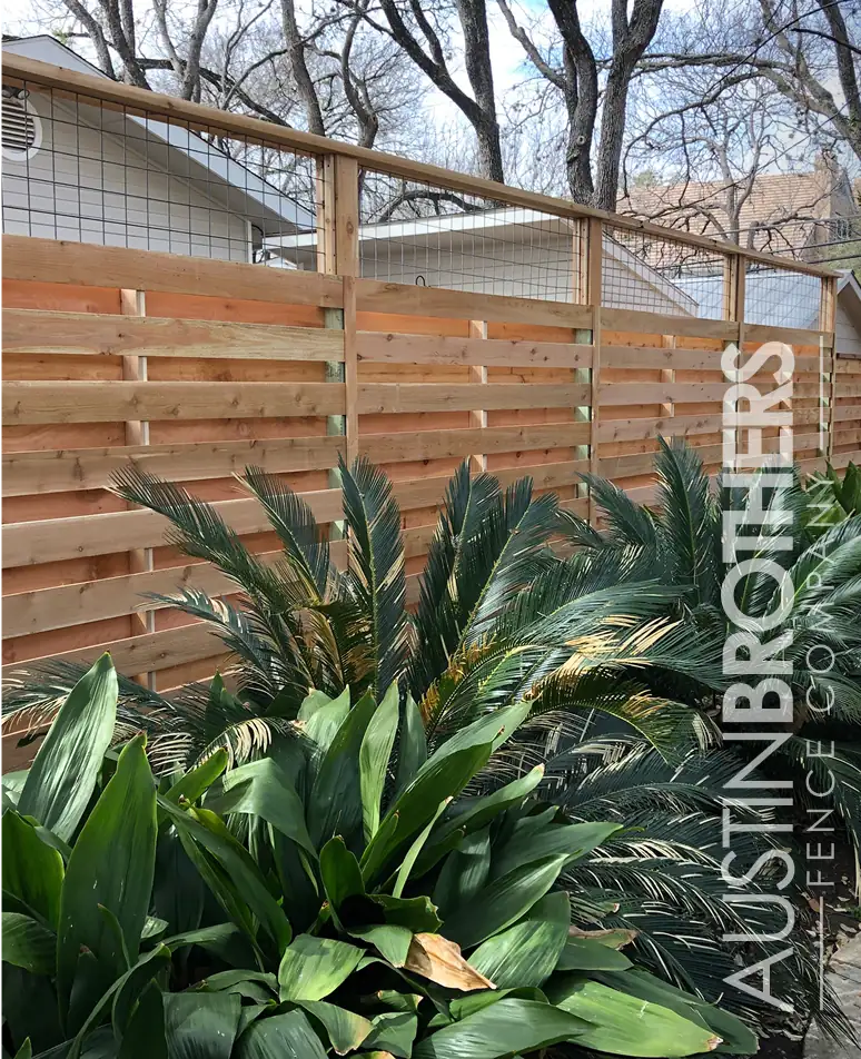Vertical fence with bull panel on top behind a lush outdoor garden.