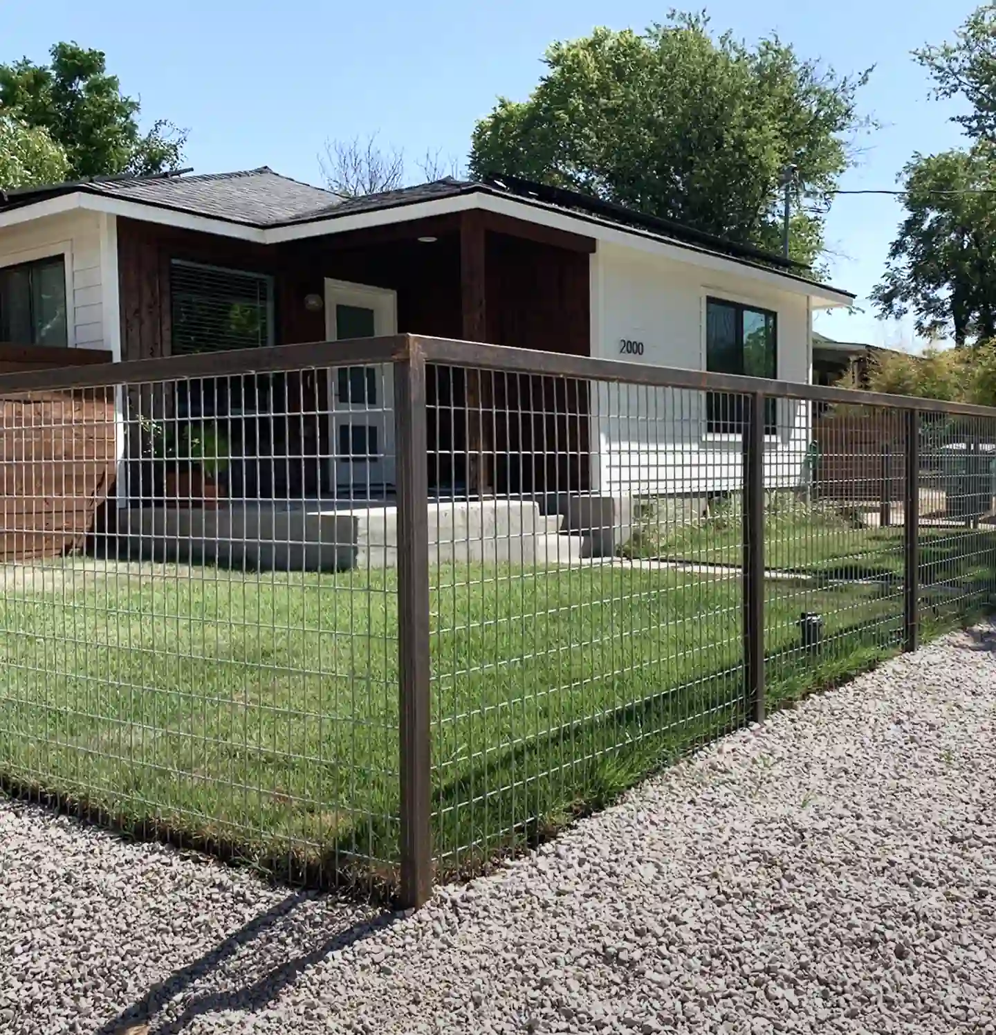 Wood-framed bull panel fence along the gravel front yard of an Austin home.