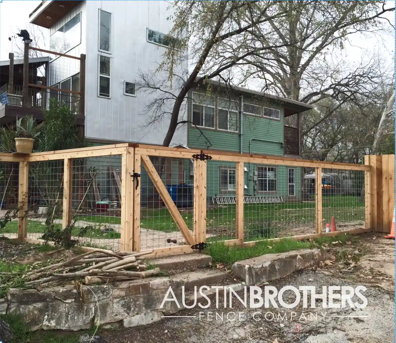 Wooden bull panel fence and gate closing off the yard of a modern Austin home.