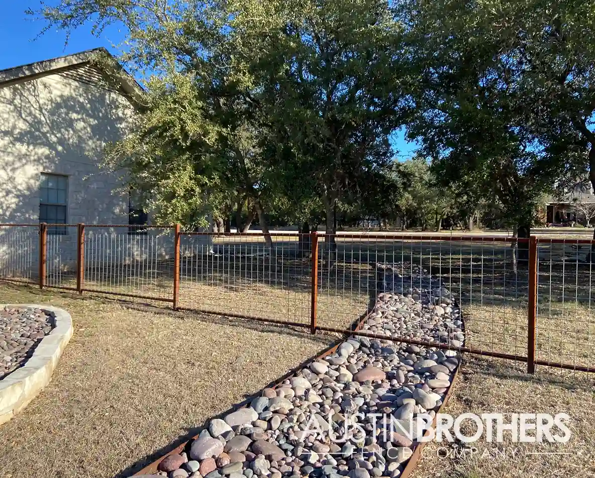 Wooden bull panel fence running alongside an Austin yard, over a rock walkway.