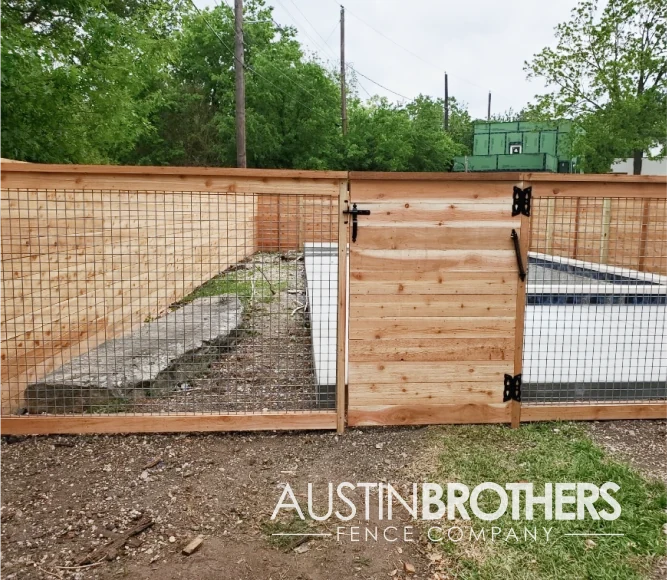 Wooden bull panel fence with a wooden gate and black latch and hinges.