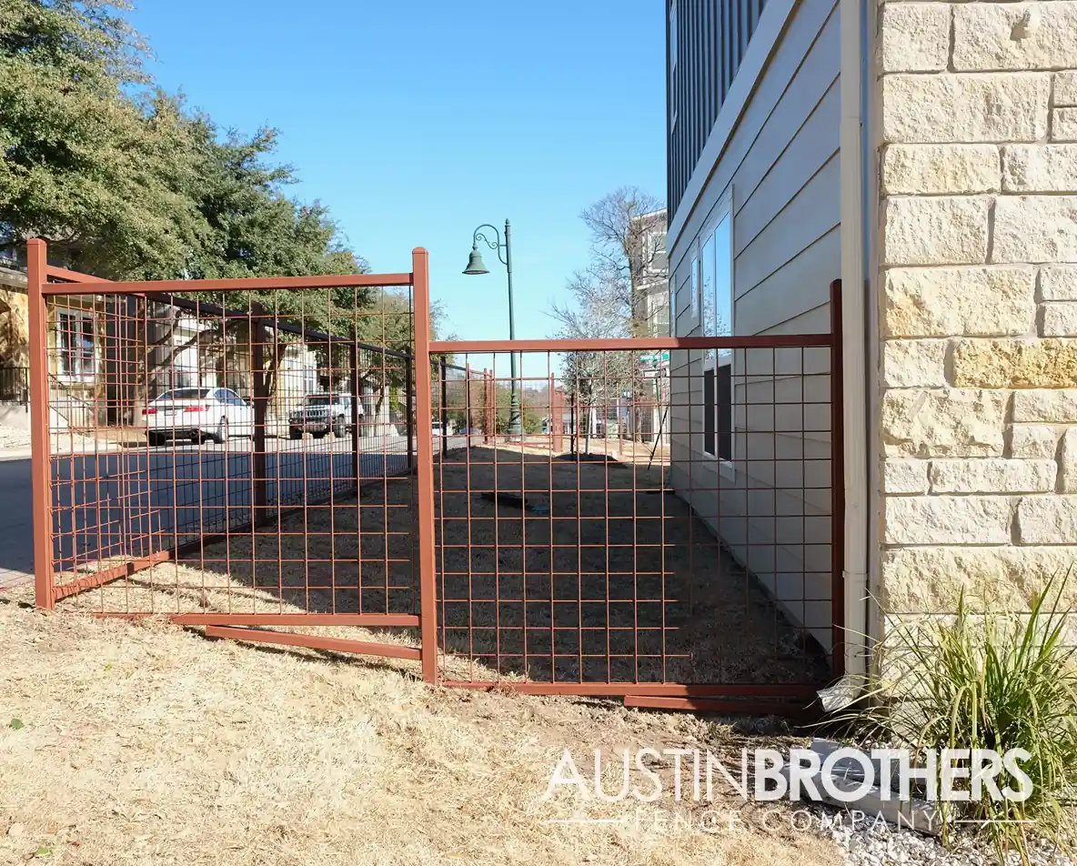 Staggered, burnt orange bull panel fence on the side yard of a home.