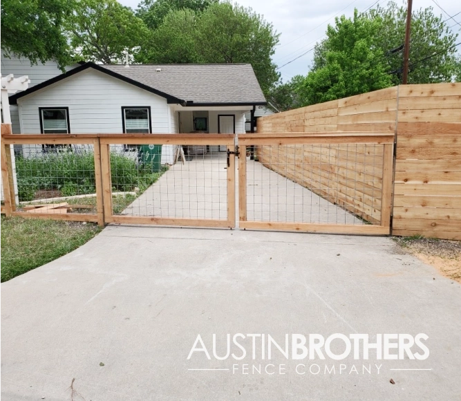 Wooden bull panel fence with a latch to lead up the driveway of a Texas home.