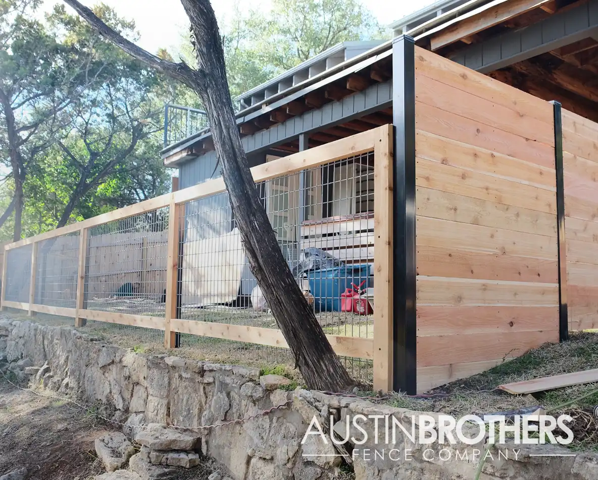 Horizontal wooden fence with steel posts cornering a wooden bull panel fence.