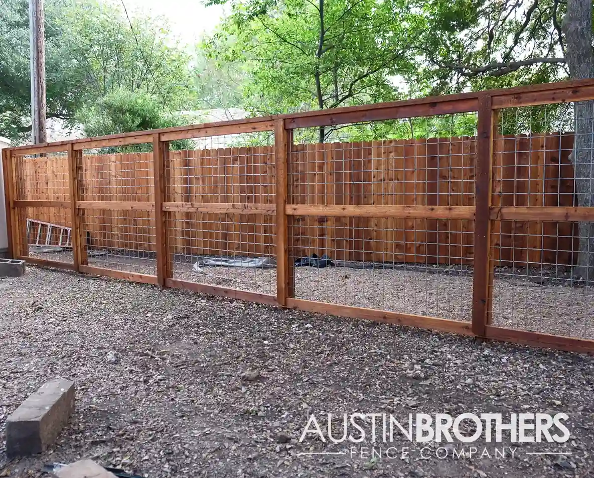 Stained wooden bull panel fence separating two areas in an Austin, Texas backyard.