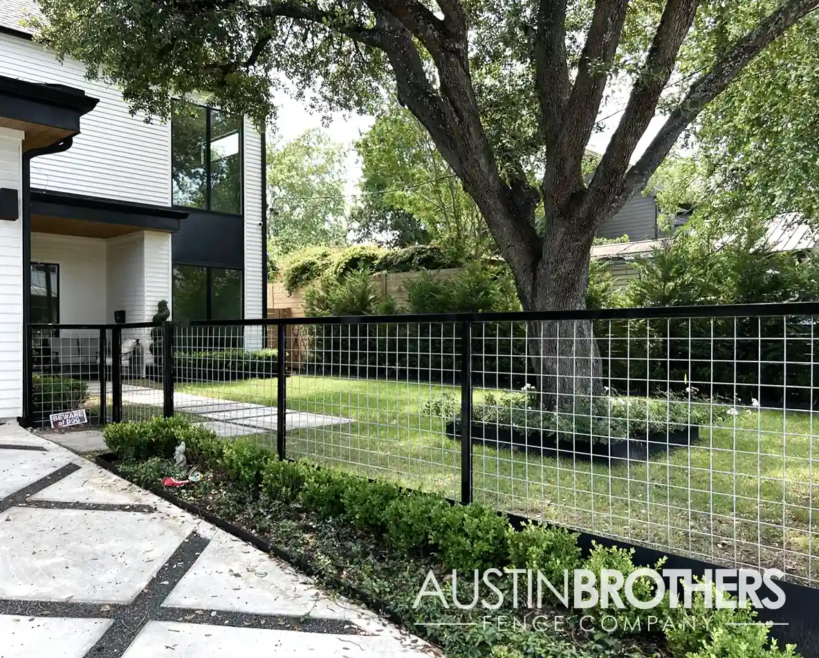 Steel bull panel fence running along the driveway of an Austin, Texas home.