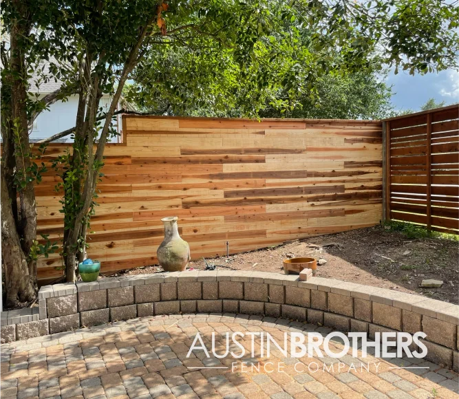 Horizontal wooden fence with multicolored boards to create a pattern.