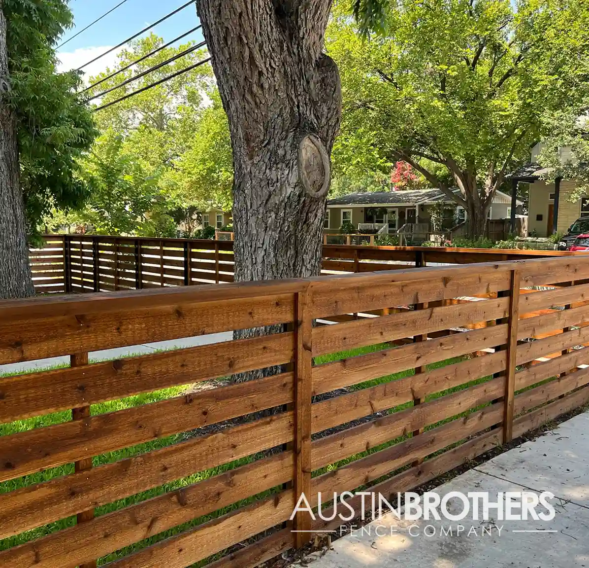 Horizontal wooden fence with a tree in the background.