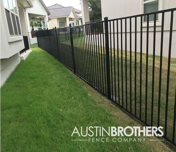 Black iron fence separating two Austin, Texas back yards.