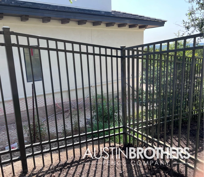 Black iron fence coming to a "T" to separate three Texas Hill Country back yards.