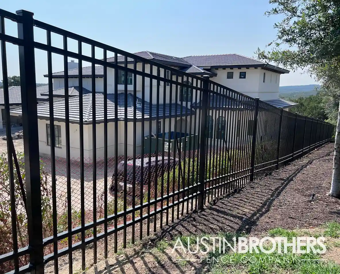 Black vertical iron residential fence overlooking a Hill Country home.
