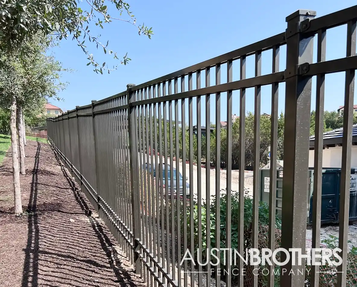 A dark gray iron fence running alongside the back property line of an Austin home.