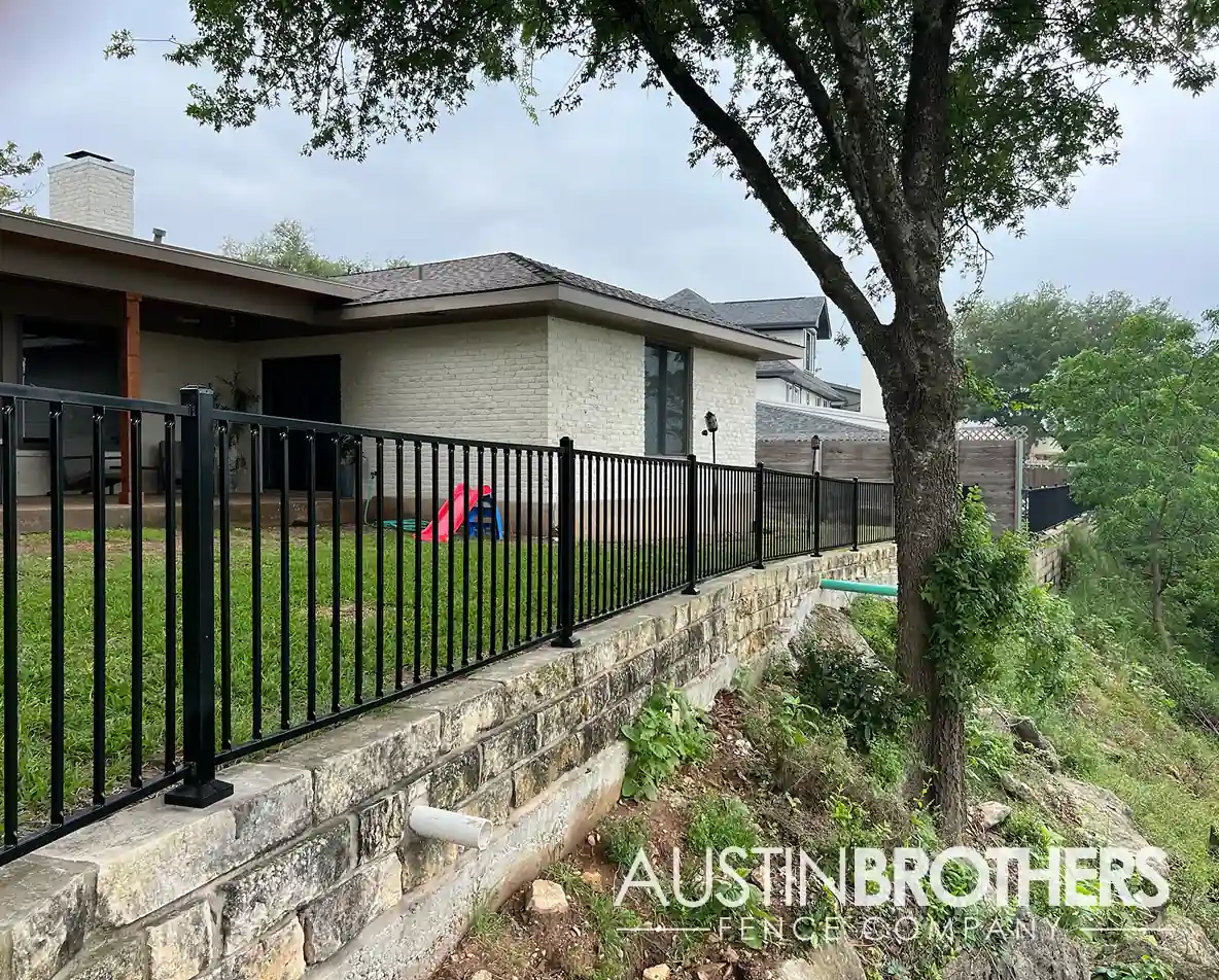 A black iron fence running alongside the back property line of an Austin home.