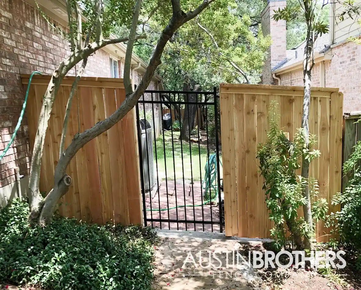 Vertical wooden fence with a see-through iron gate entering an Austin backyard.