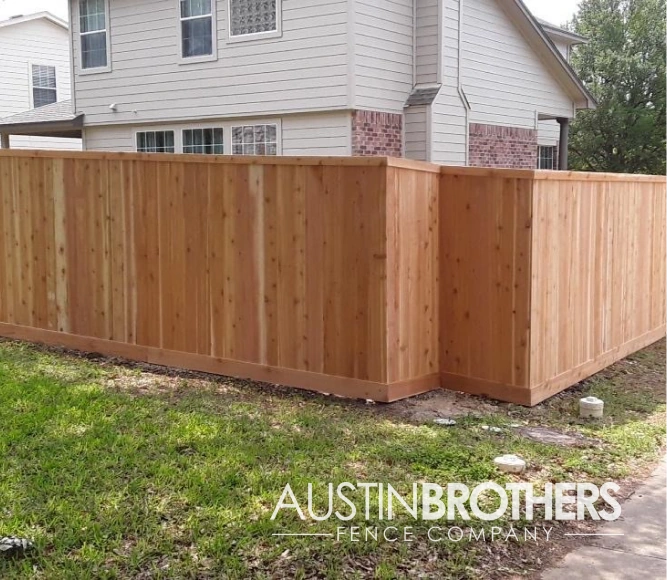 Capped vertical wooden fence with a corner indent.
