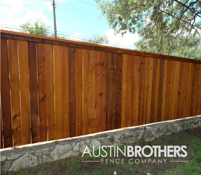 Capped vertical fence on top of a stone wall.