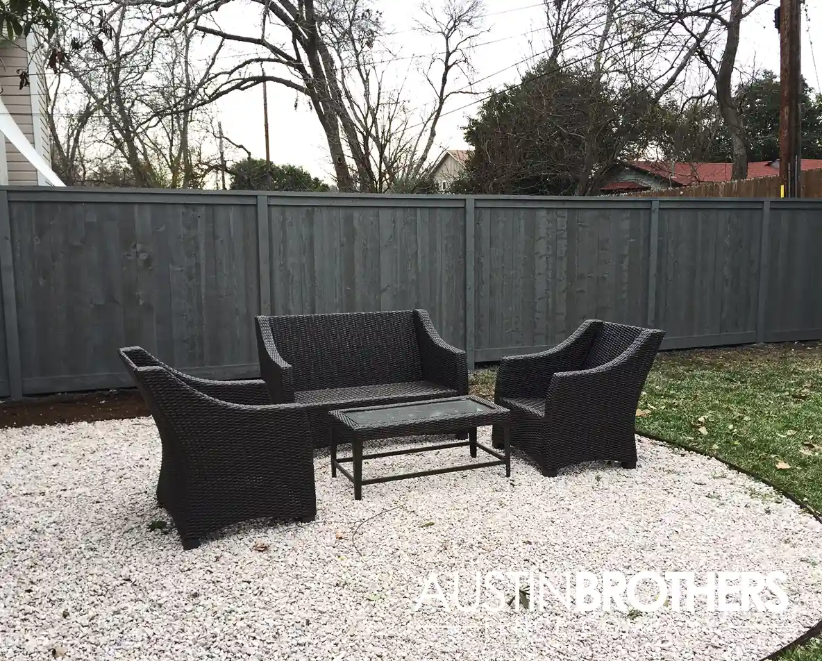 Black-stained vertical wooden fence behind black outdoor furniture.