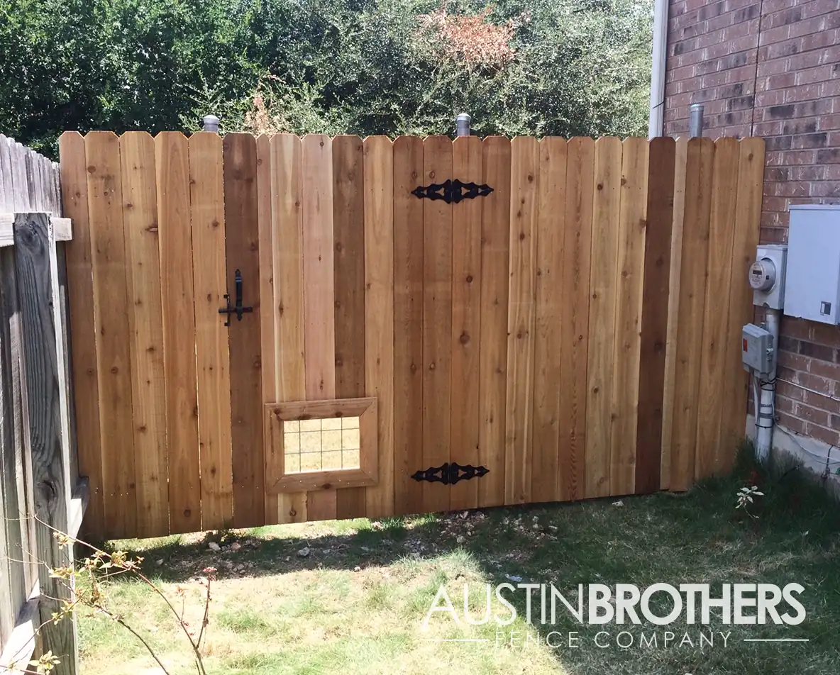 Vertical wooden fence with steel latch gate and a bull panel window that's dog-height.